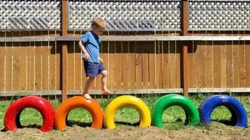 Child Playing on DIY Rainbow Tire Obstacle Course in Backyard