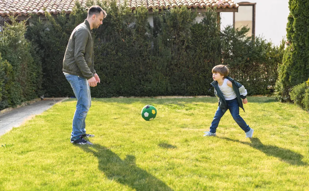 Father and Son Playing Soccer in Backyard