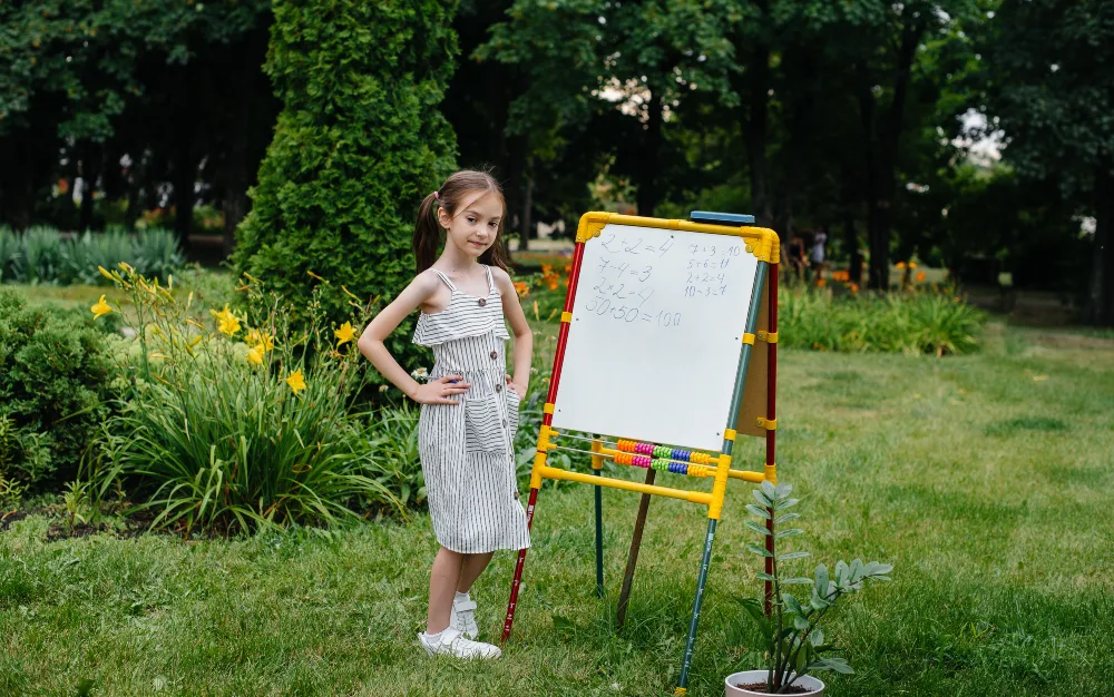 Little Girl Teaching with Backyard Easel and Abacus
