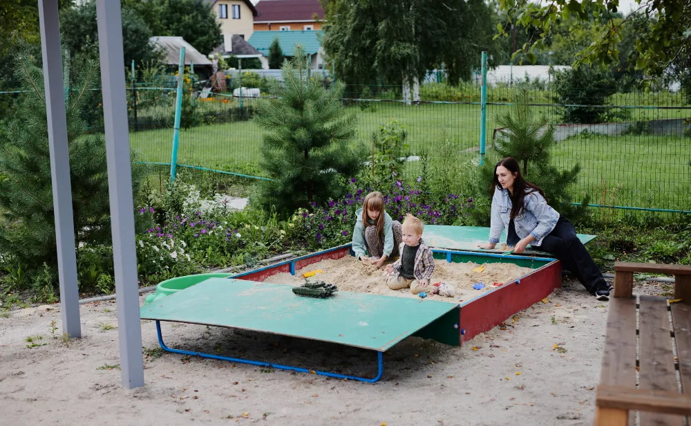 Mom and Kids Building Worlds in Backyard Sandbox