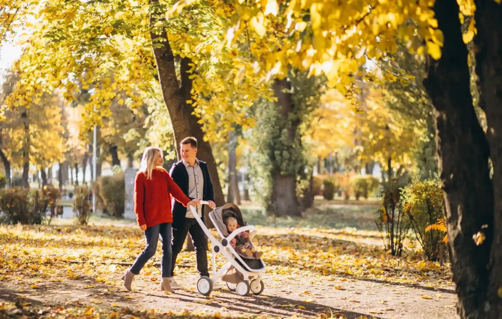 Parents Strolling with Baby in Autumn Park